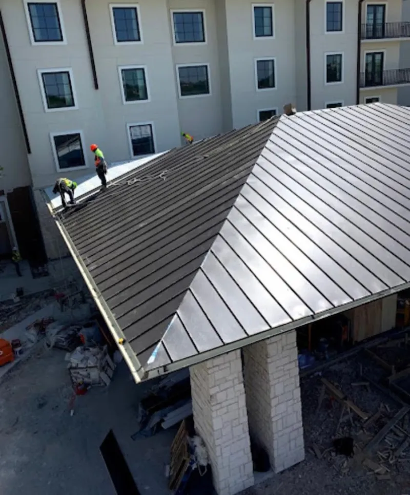 Crew installing standing seam metal roof panels on a commercial project in Moreau